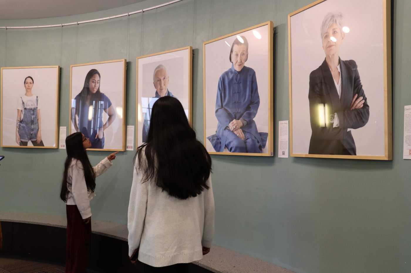 Students admiring 200 Women exhibition portraits on a gallery wall