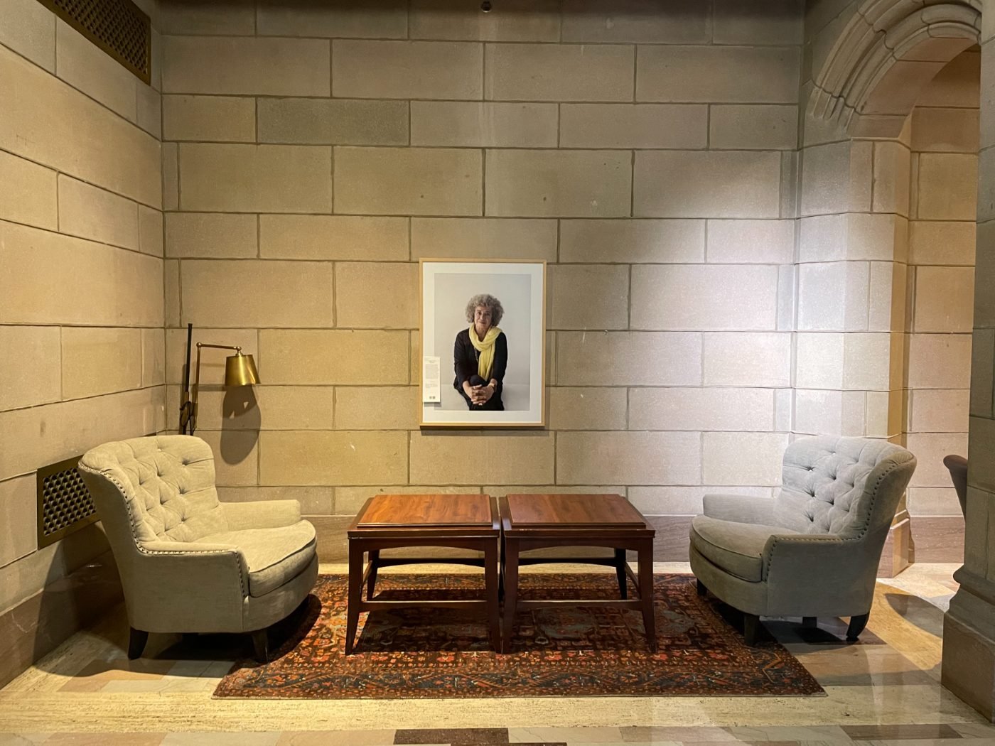 Intimate exhibition lounge with a single framed 200 Women portrait above seating