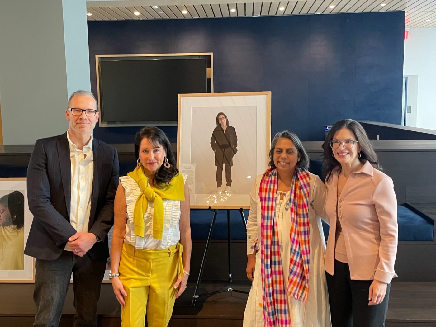 Host institution organizers presenting a framed 200 Women portrait at the exhibition